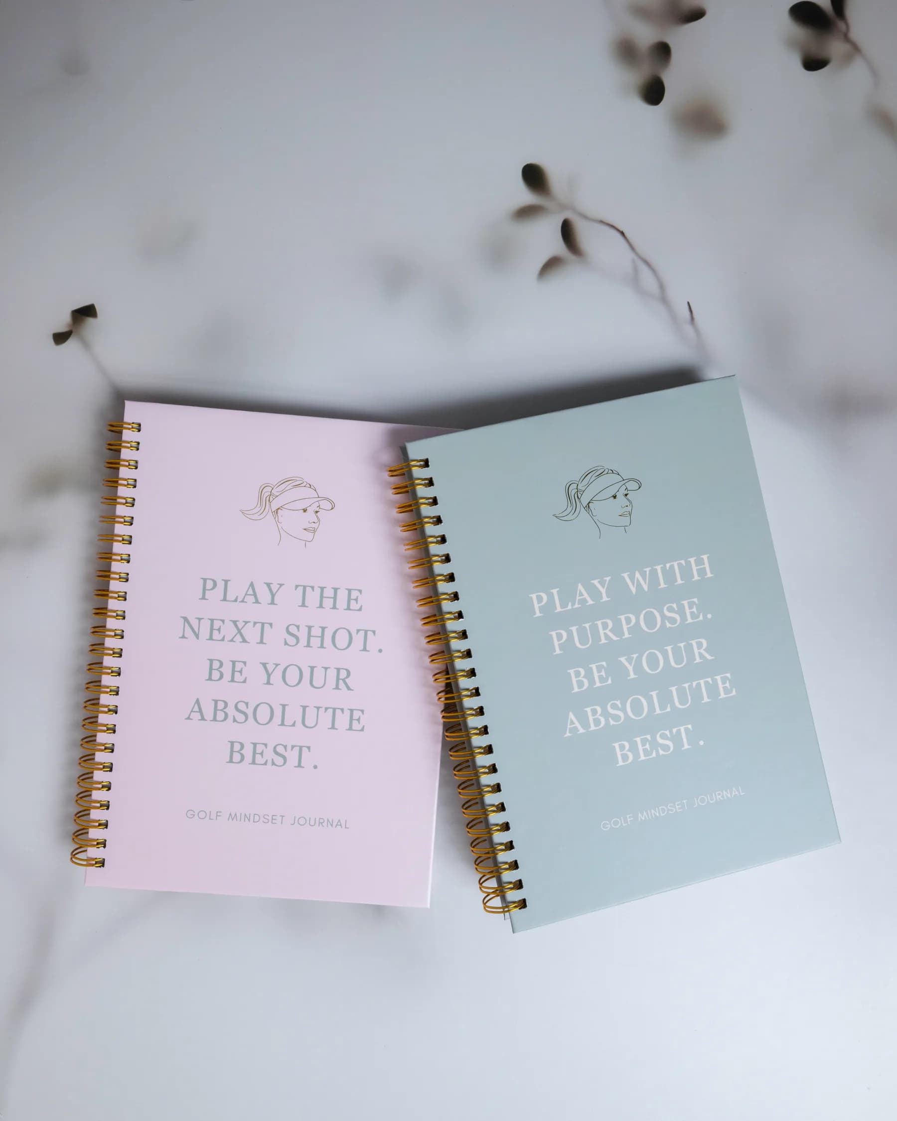 The Play With Purpose and Play The Next Shot golf mindset journals laid flat in soft natural light